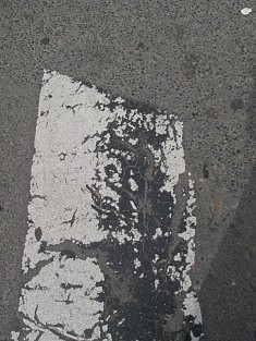 Photo d'une bande blanche usée de passage piéton place Edith Piaf.