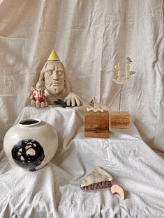 Trois univers céramiques se rencontrent : la sculpture satirique de Jésus par Léa Rose dialogue avec les mobiles délicats de Justine Cornuot et le vase « Moon Var » de Formes, signé Camille De Landtsheer, reconnaissable à son émail coulé.